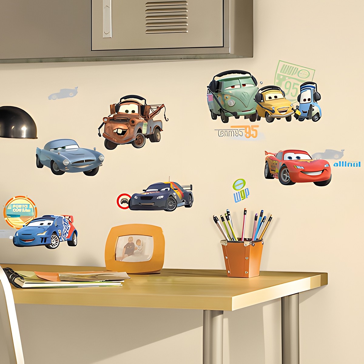 RoomMates Wandsticker Disney Pixar Cars, Lightning McQueen, Mater und weitere Cars-Figuren an einer cremefarbenen Kinderzimmerwand über einem Schreibtisch