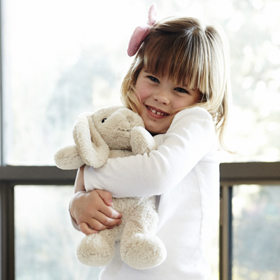 Cloud b sleep aid Bubbly Bunny, lifestyle photo of smiling girl hugging beige bunny plush