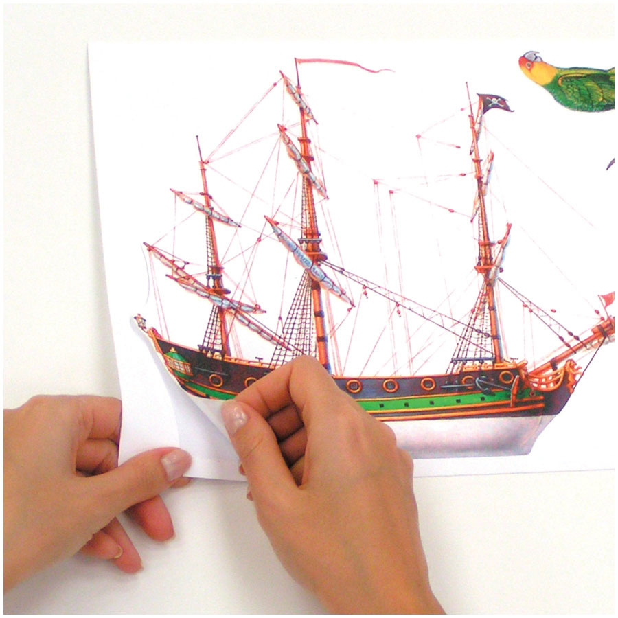 RoomMates wall decal Pirates, hands peeling a sailing ship motif off the backing sheet, usage example