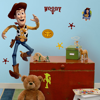 RoomMates wall decal Disney Pixar Toy Story Woody, Woody in a jumping pose with a cowboy hat on a blue children's room wall above a red chest with a teddy bear