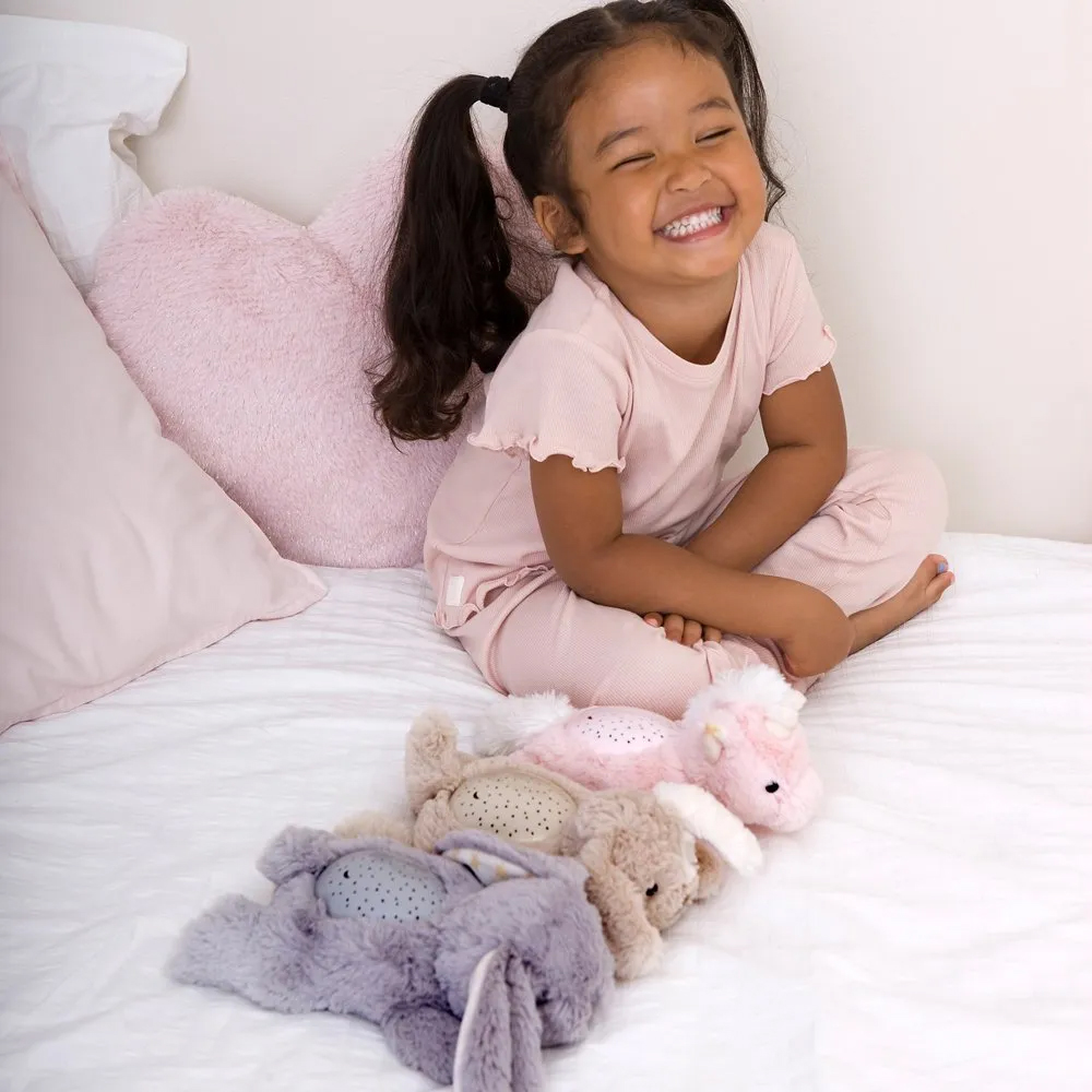 Cloud b sleep aid Dream Buddies, group photo of laughing cross-legged girl with three plush toys in a row