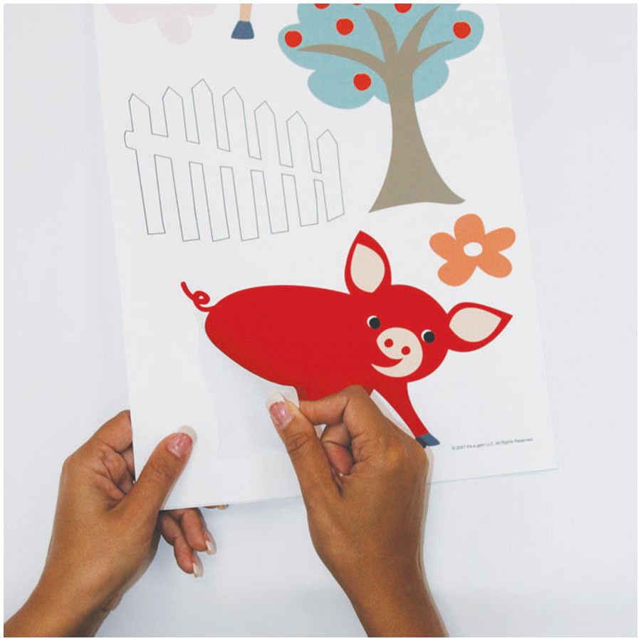 RoomMates wall decal Gem's Friends Farm, hands peeling a piglet motif off the backing sheet, usage example