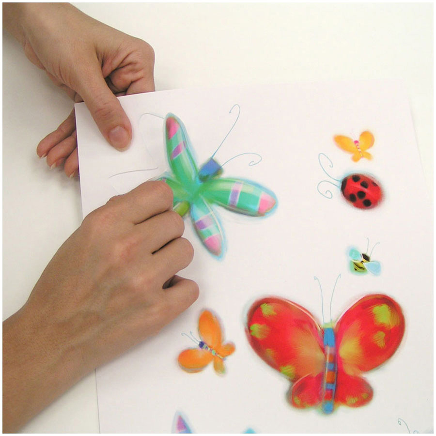 RoomMates wall decal Jelly Bugs, hands peeling a dragonfly motif off the backing sheet, usage example