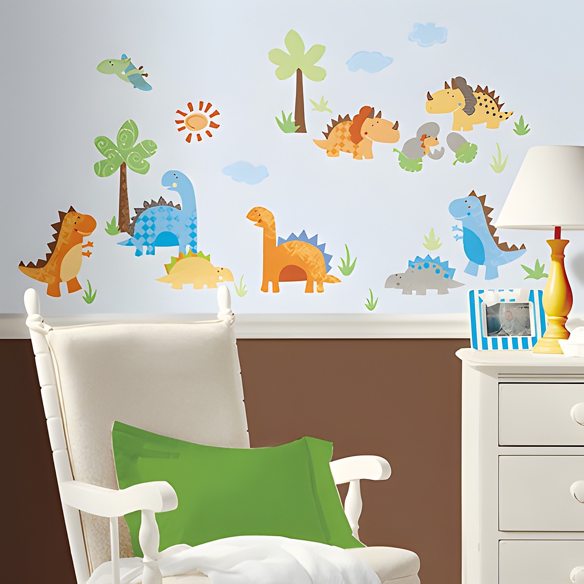 RoomMates Wandbild Babysaurus, bunte Dinosaurier-Motive mit Palmen und Sonne an einer hellblauen Kinderzimmerwand hinter einem Schaukelstuhl