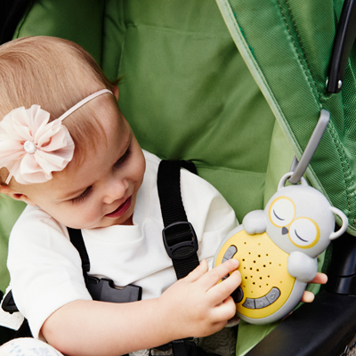 Cloud b sleep aid Sweet Dreamz on the Go owl, lifestyle photo of baby in stroller touching the device