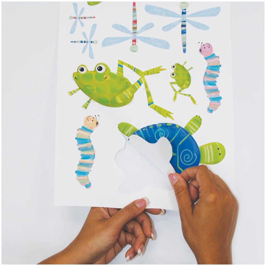 RoomMates wall decal Hoppy Pond, hands peeling a frog and dragonfly motif off the backing sheet, usage example