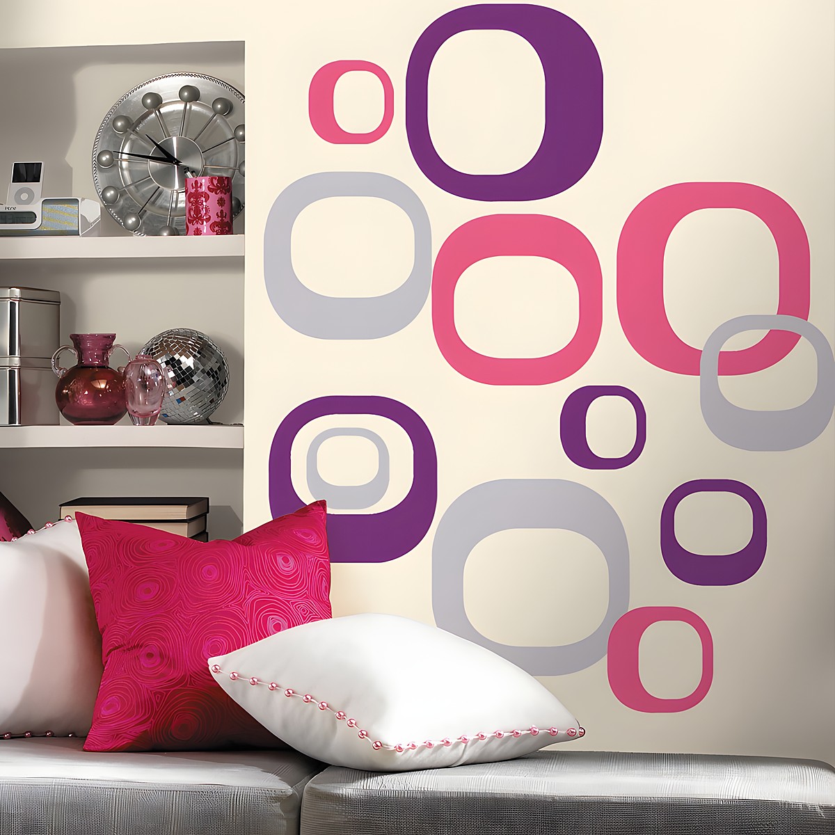RoomMates Wandbild Modern Ovals, pinke, lila und graue Ovalringe an einer cremefarbenen Wand neben einem Regal