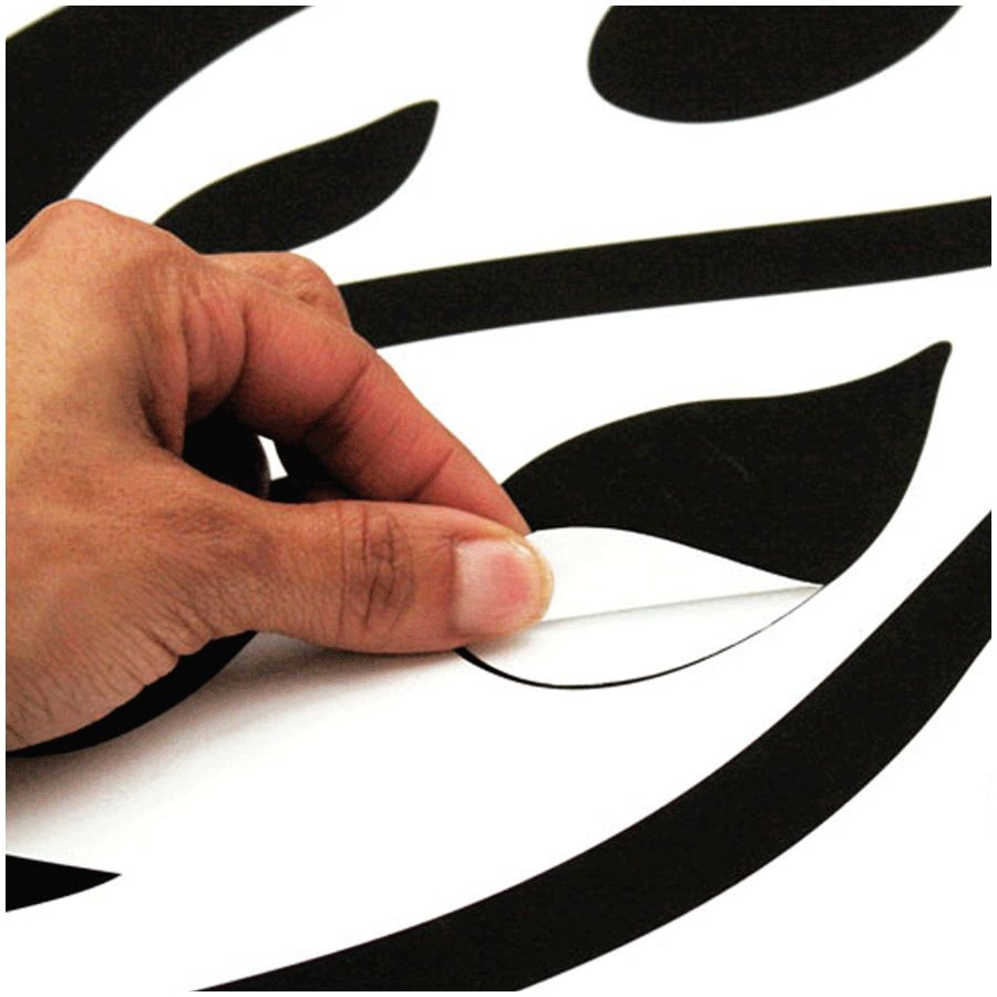 RoomMates wall decal Tree Branches, hand peeling a black leaf motif off the backing sheet, usage example