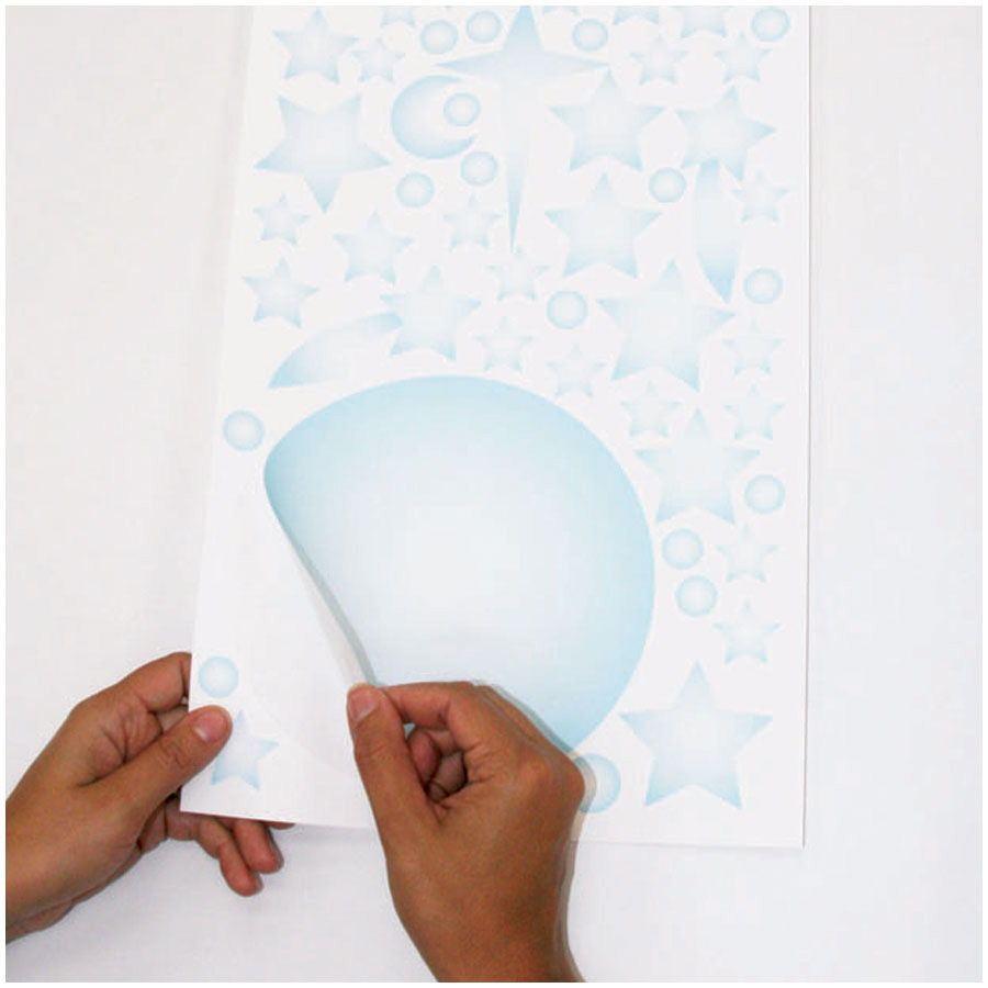 RoomMates wall decal Celestial, hands peeling a large planet decal off the backing sheet, usage example