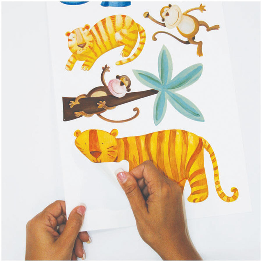 RoomMates wall decal Jungle Adventure, hands peeling a tiger motif off the backing sheet, usage example