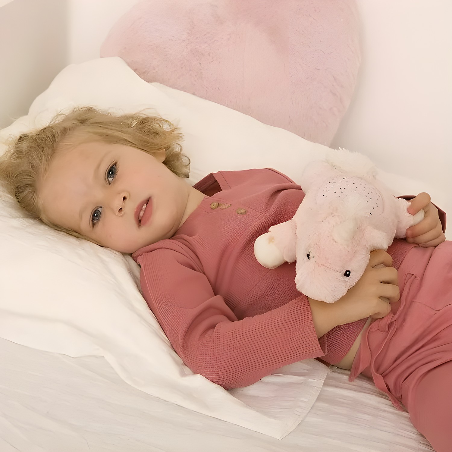 Cloud b sleep aid Dream Buddies unicorn, lifestyle photo of toddler lying in bed hugging pink plush toy