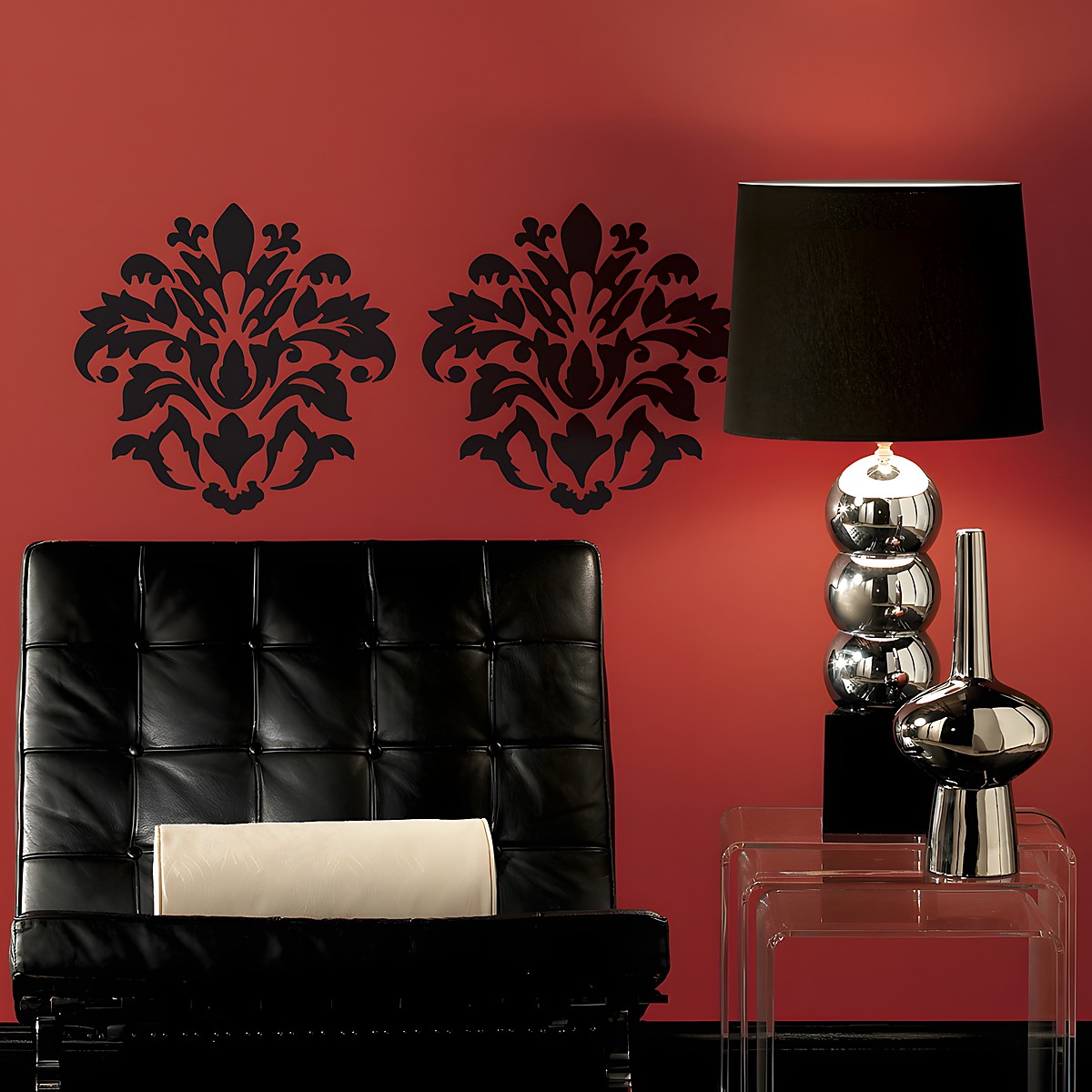 RoomMates Wandbild Damask Peel & Stick, zwei schwarze Damast-Ornamente an einer roten Wand hinter einem schwarzen Ledersessel