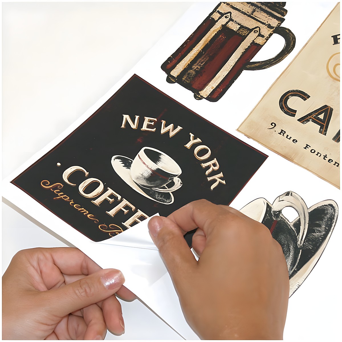 RoomMates Wandsticker Coffee House Peel & Stick, Hände lösen ein New-York-Coffee-Schild-Motiv vom Trägerbogen, Anwendungsbeispiel