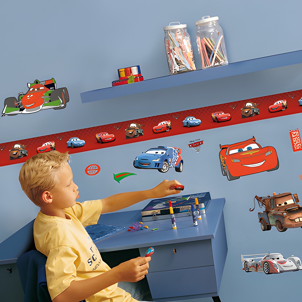 decofun wall decoration Pixar Cars 2 on a blue children's room wall with a red border, boy at a desk with race car Francesco Bernoulli above