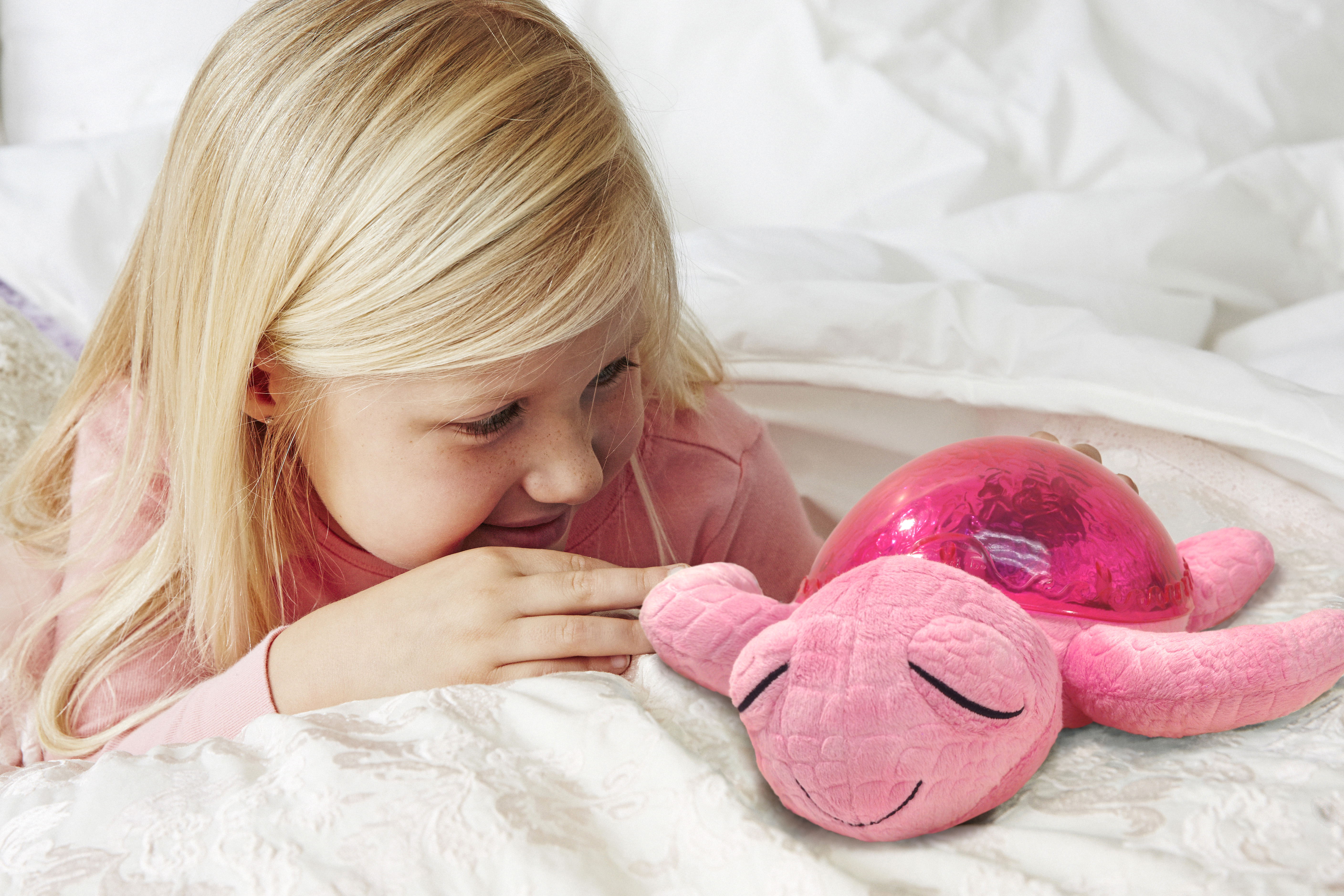 Cloud b sleep aid Tranquil Turtle Pink, lifestyle photo with girl and pink plush toy in bed