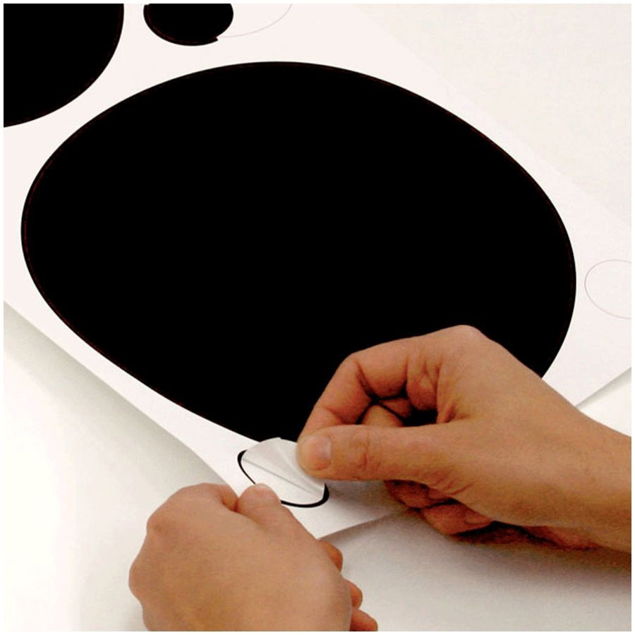 RoomMates wall decal Black & White Dots Peel & Stick, hands peeling a black dot decal off the backing sheet, usage example