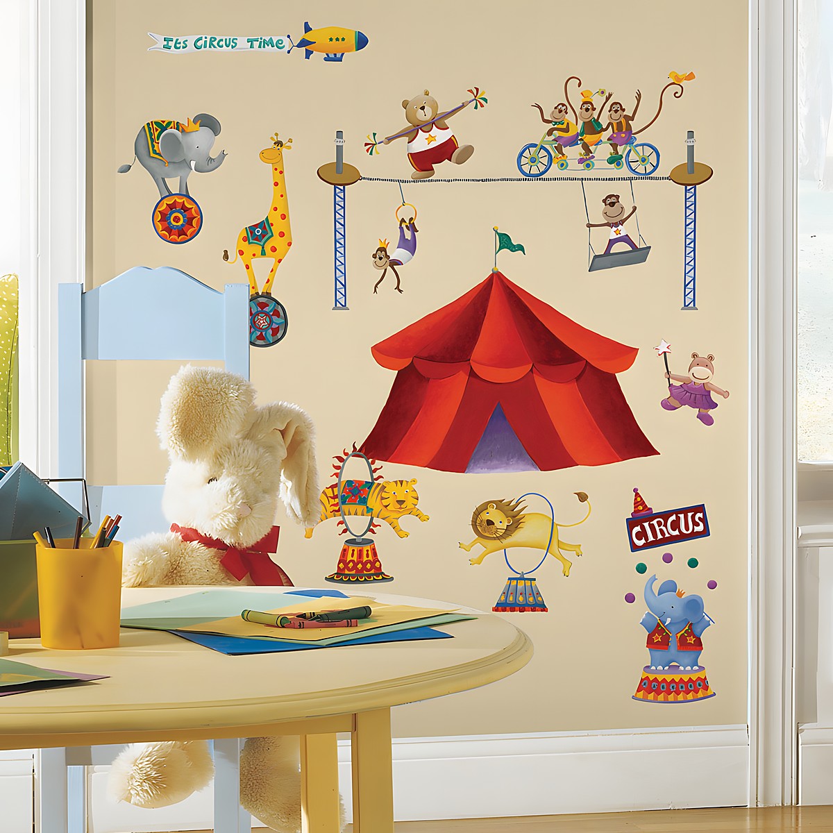 RoomMates Wandsticker Circus, bunte Zirkusmotive mit Zelt, Elefant, Löwe und Affen an einer beigen Kinderzimmerwand über einem Kindertisch