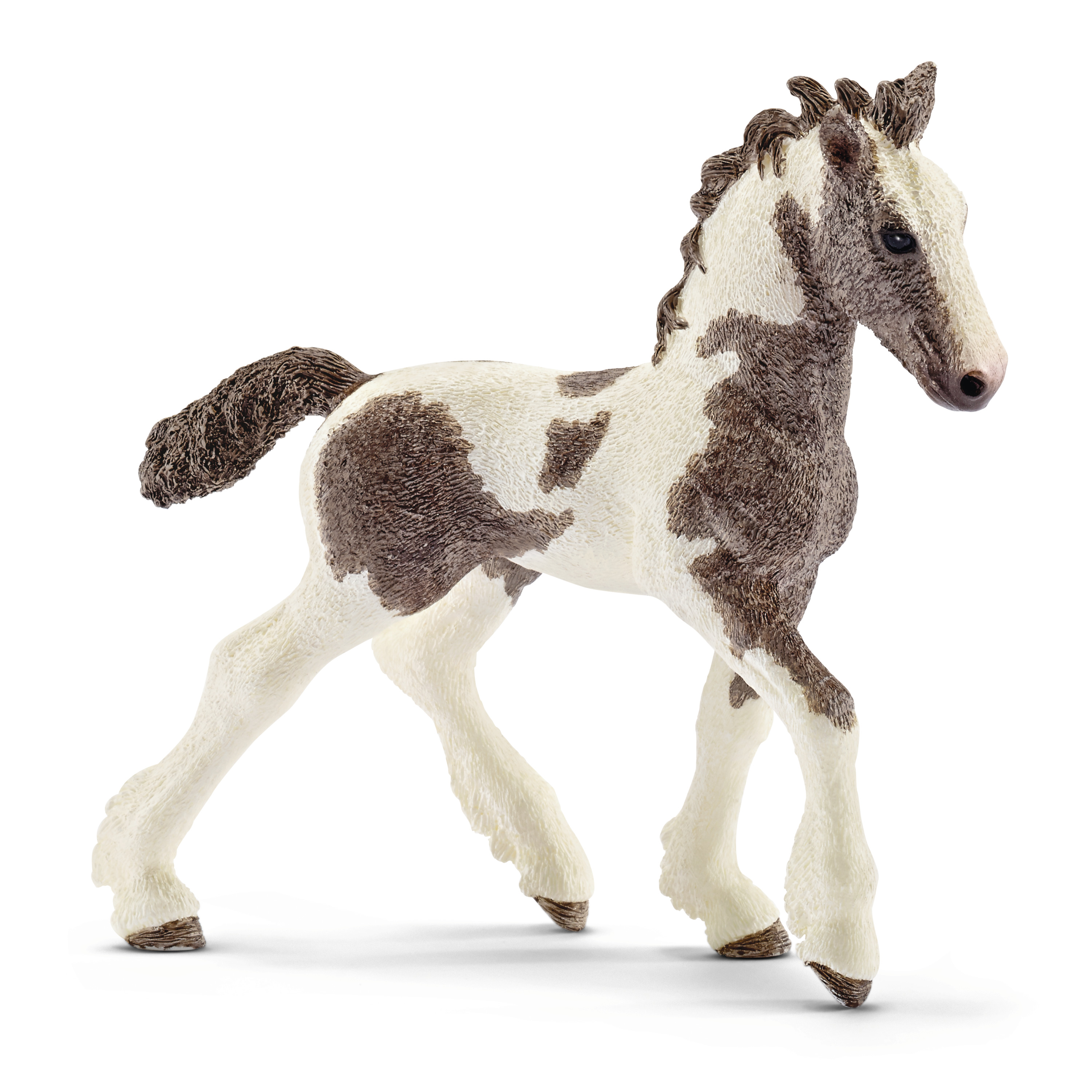 Schleich Farm World Tinker foal, toy figure with brown and white piebald coat and a curly mane, walking