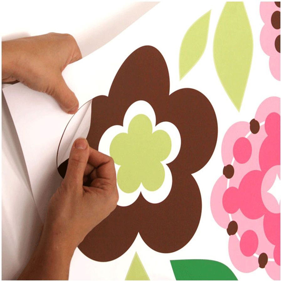 RoomMates wall decal Growing Flowers, hands peeling a brown and green flower motif off the backing sheet, usage example