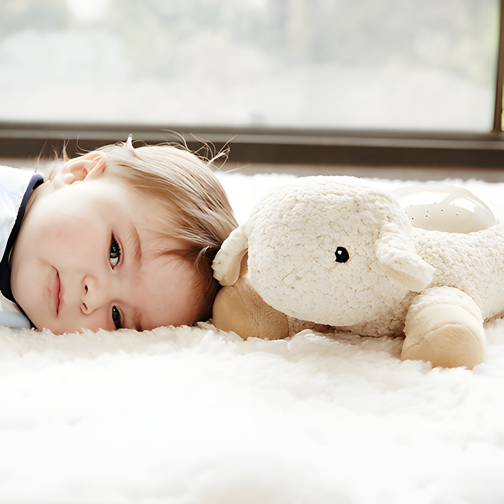 Cloud b sleep aid Twilight Buddies rabbit, lifestyle photo with toddler lying next to the plush toy