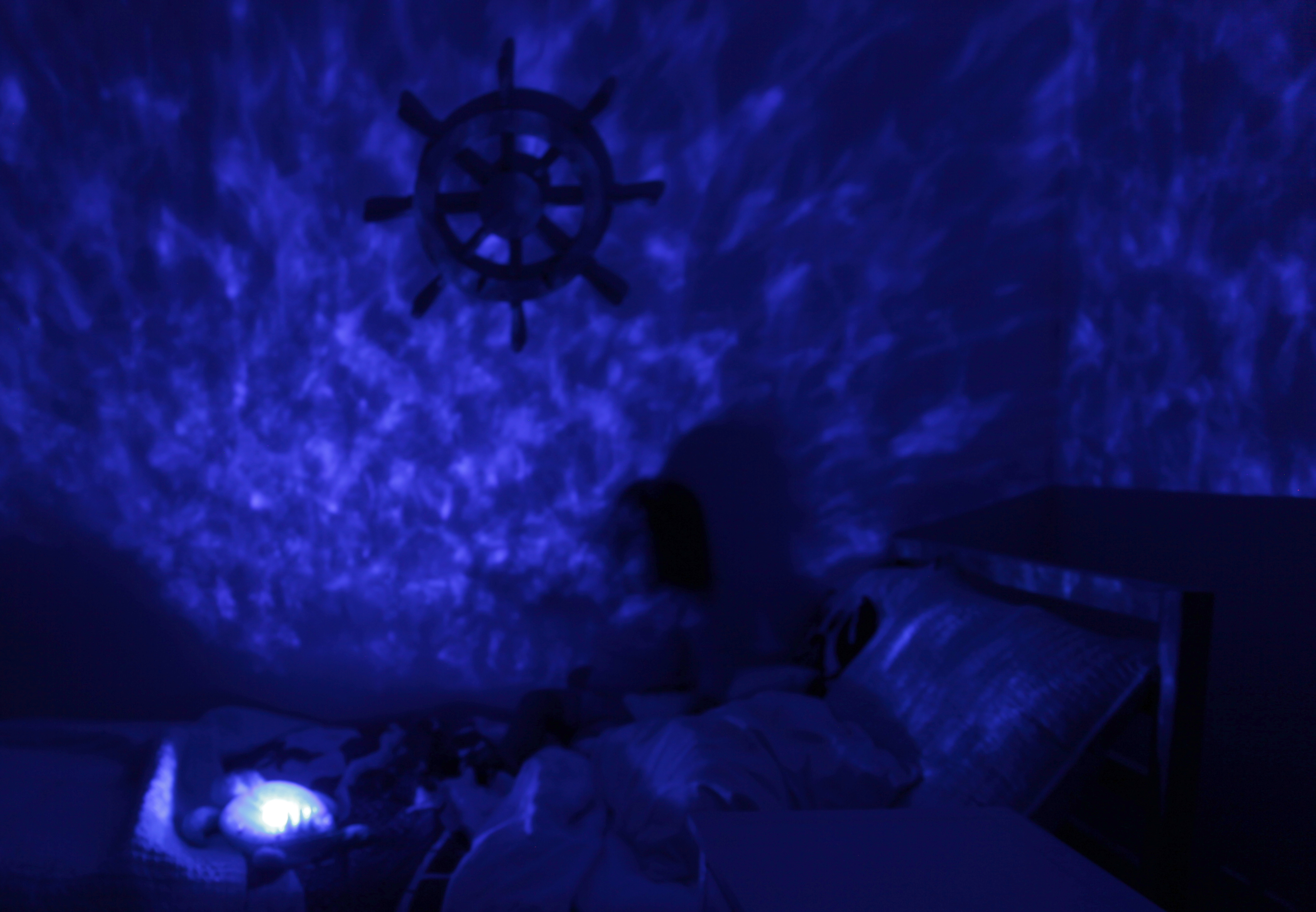 Cloud b sleep aid Tranquil Turtle Pink, lifestyle photo with light projection in a darkened bedroom
