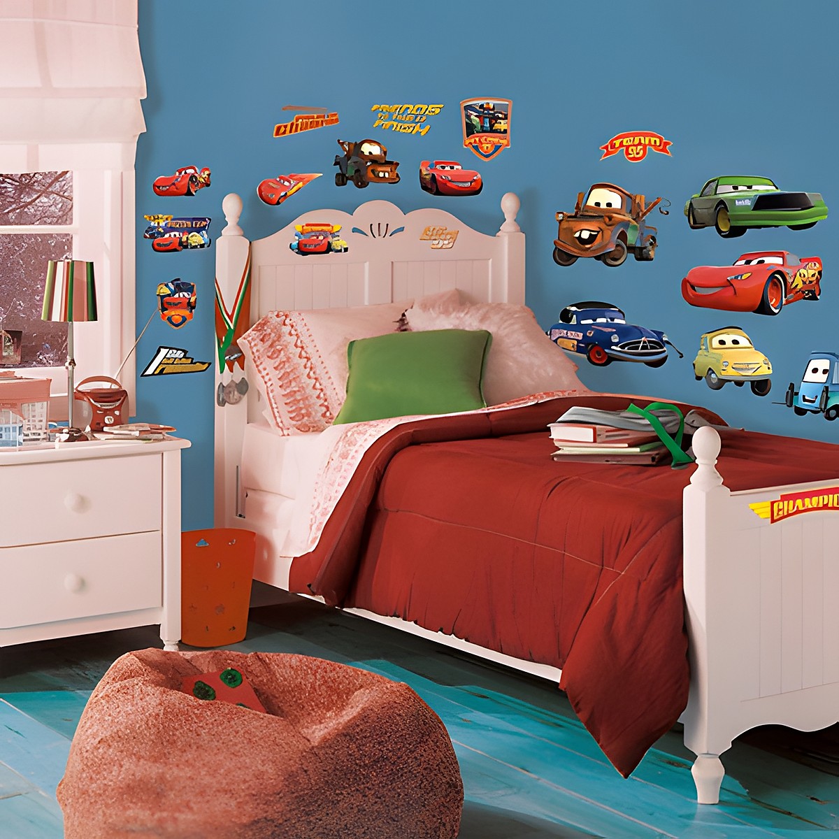RoomMates Wandsticker Disney Pixar Cars Piston Cup Champions, Lightning McQueen, Mater und weitere Cars-Figuren an einer blauen Kinderzimmerwand über einem Bett